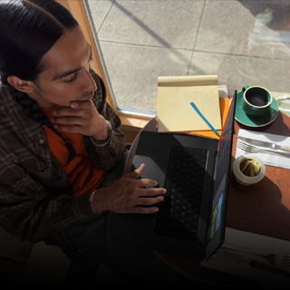 Person working on an unplugged MacBook Pro in a coffee shop setting